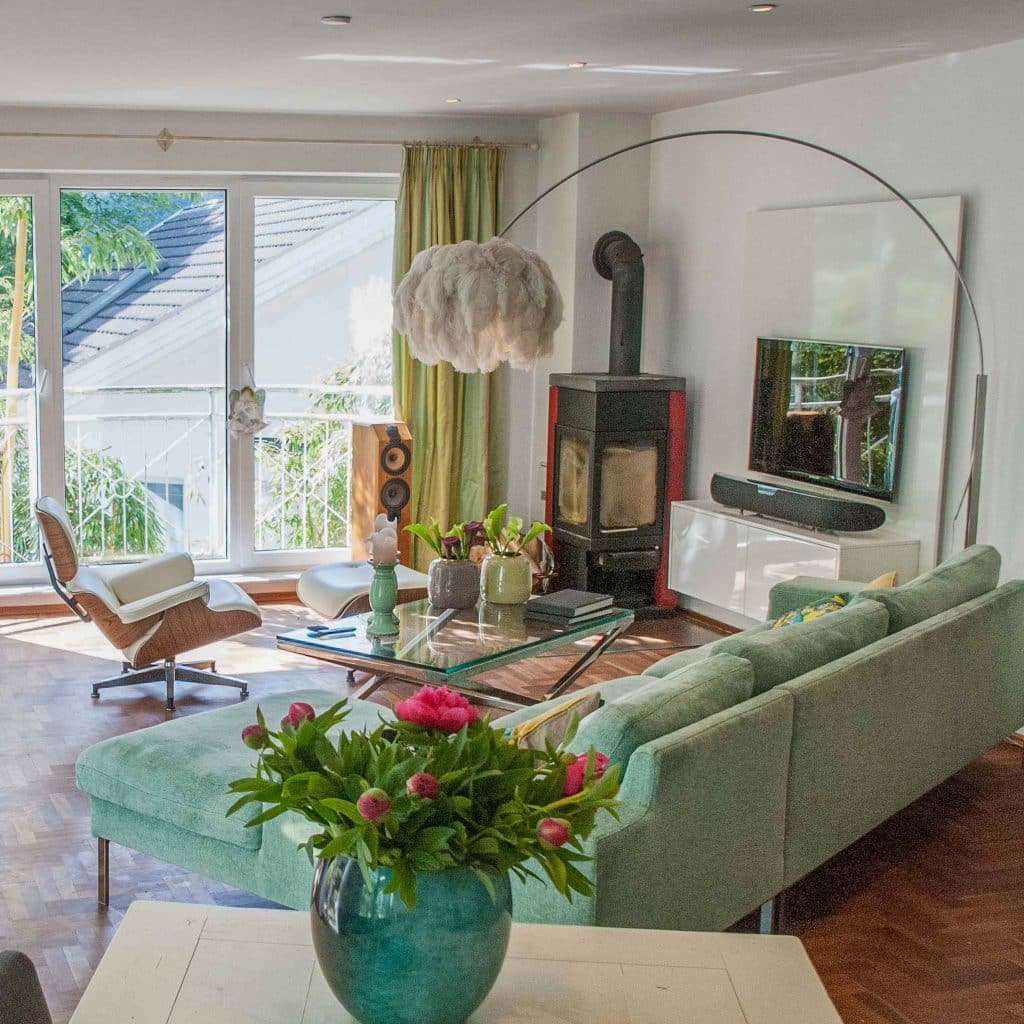 Offenes Wohnzimmer mit Kamin, grünem Sofa, Bogenleuchte und Designmöbeln