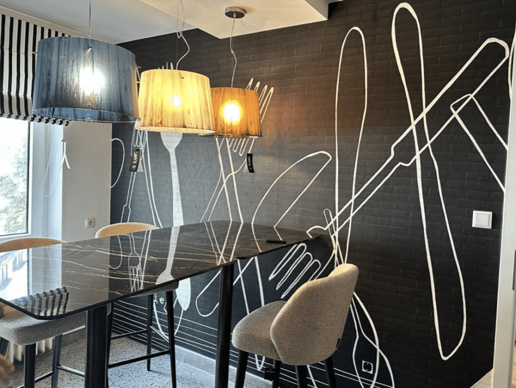 Esszimmer nach der Neugestaltung mit dunklem Wandmotiv und filigranen Designleuchten