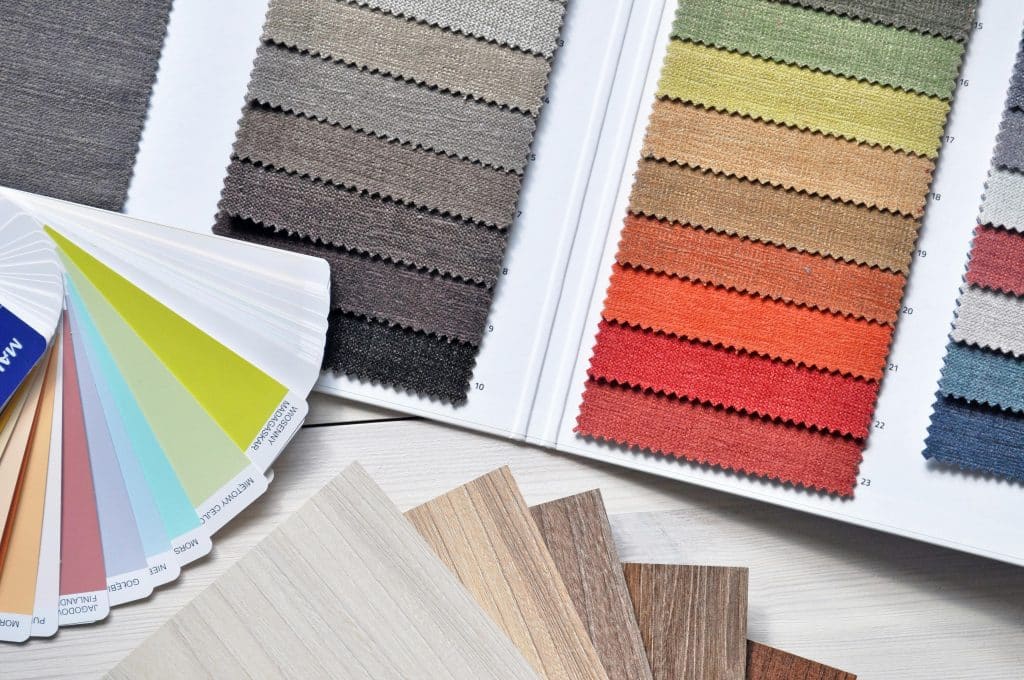 Vielseitige Materialmuster bei WDW Interior Design mit bunten Stoffproben, Farbfächer und Holzdekoren für die individuelle Raumplanung
